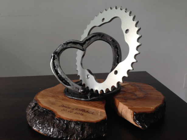 wedding present - Connection of a heart made of horseshoes and a sprocket fixed on an engraved wooden plate.